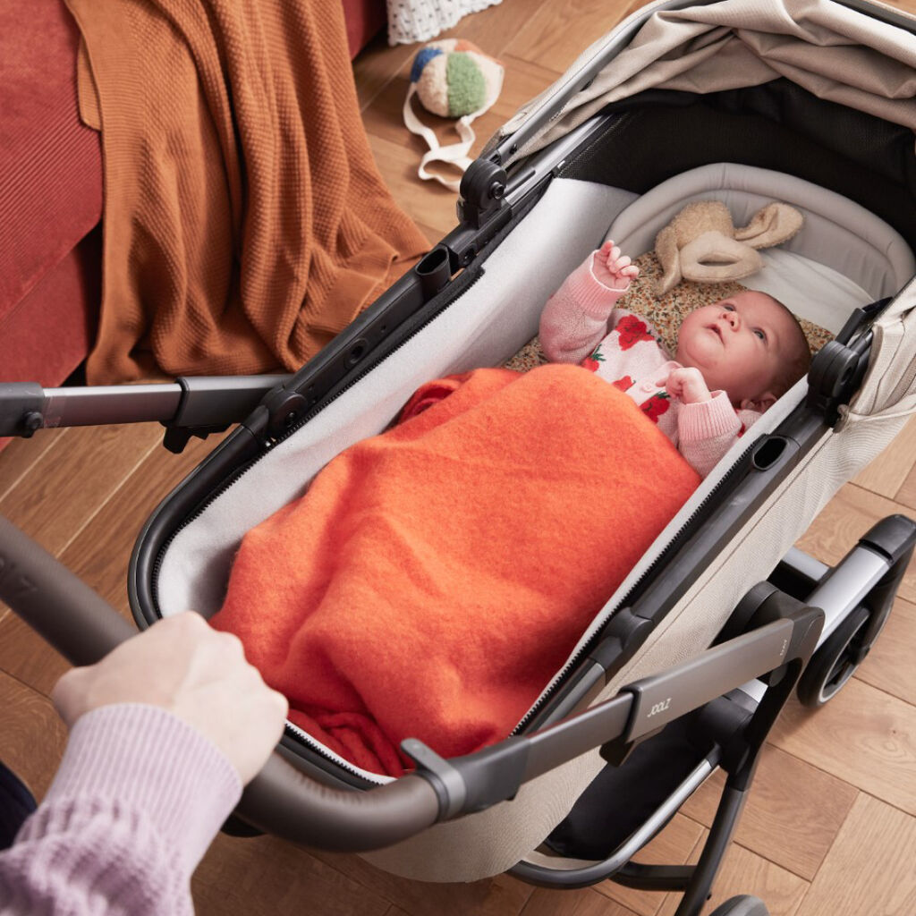 Baby resting in the carrycot of a Joolz Day5 pushchair, wrapped in a cosy blanket.